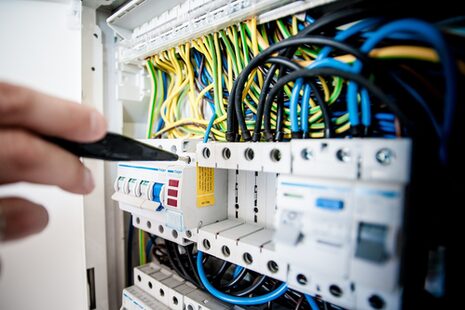 Test aleti taşıyan bir el elektrik kontrol kabinine uzanıyor