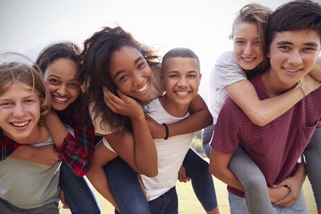 Kinder und Jugendliche tragen sich huckepack und lachen