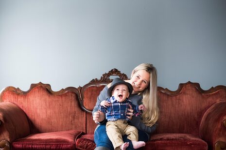 Une femme assise sur un canapé avec un enfant souriant sur les genoux