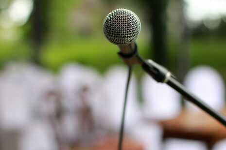 A microphone on an open-air stage, with a blurred view of the audience in the background